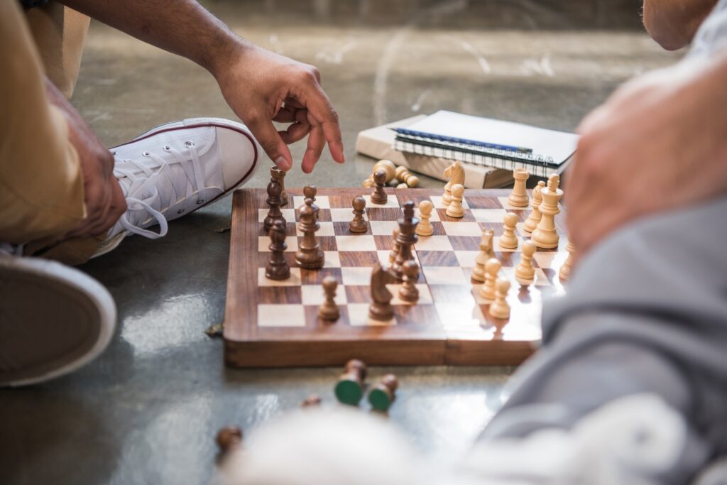 young men sitting on floor and playing chess on chess board